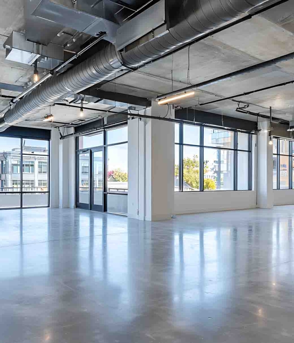 Spacious, bright modern office space features polished concrete floors, exposed ductwork, track lighting, and expansive windows offering city views. Clean, contemporary design.